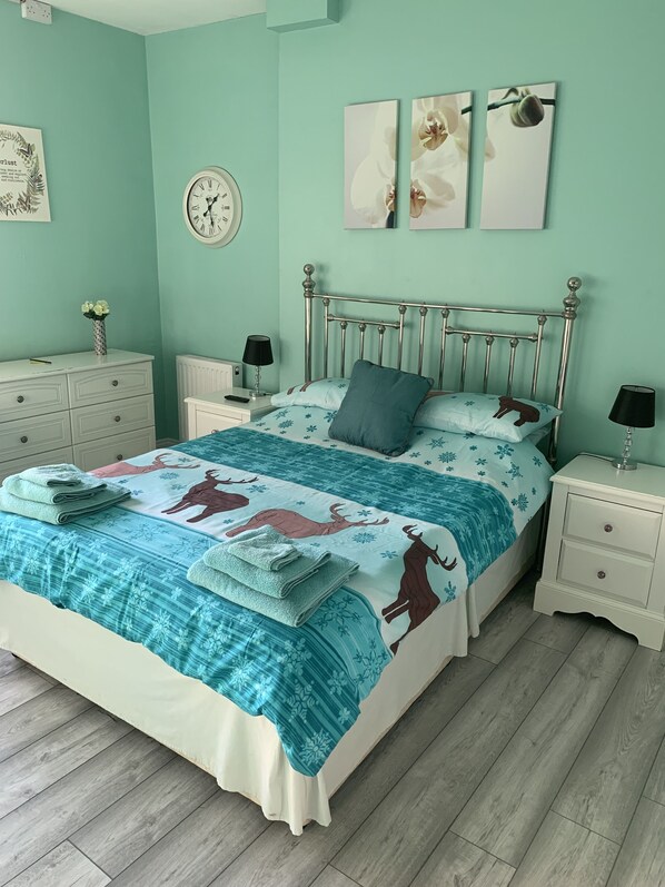A bedroom with a bed, nightstands, a dresser, and a wall clock. - Bedrocklodge Buisness Centre Holidaylets (Bristol)