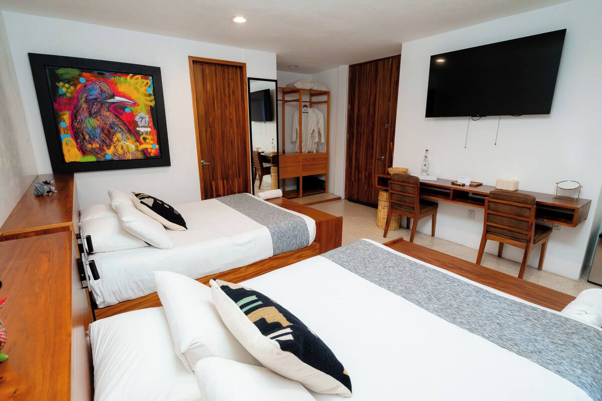 Ein Hotelzimmer mit zwei Betten, einem Schreibtisch, einem Fernseher und einem Gemälde.