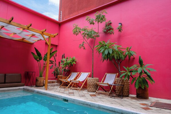 Un espace piscine agrémenté de chaises longues, de plantes en pot et d’une pergola.