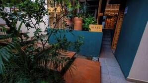 A narrow indoor space with a blue wall, a wooden staircase, and potted plants. -  Hotel Boutique Casa de Arte (Oaxaca)
