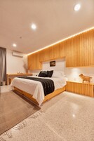 A modern bedroom with a wooden bed frame, a bedside table, a nightstand, and a wall-mounted shelf.