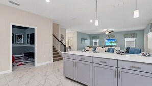A modern kitchen with grey cabinets, a white countertop, and a built-in stove. - Movie Theater! Private Pool Oasis! Resort Near Disney! 2707 (Kissimmee)