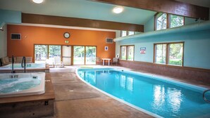 Una piscina interior con un jacuzzi de 90 centímetros, sillas de descanso y un reloj en la pared.