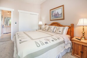 A bedroom with a large bed, a wooden headboard, a bedside table with a lamp, and a framed picture on the wall. - Walk to Shops! Beautiful Views On Lake Dillon + Hot Tubs & Pool (Dillon)