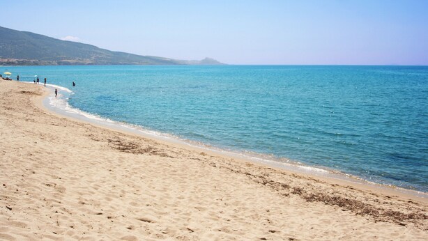 A sandy beach with clear blue water and a distant mountain. - Affittimoderni Castelsardo Lentisco - Csle03 (Castelsardo)
