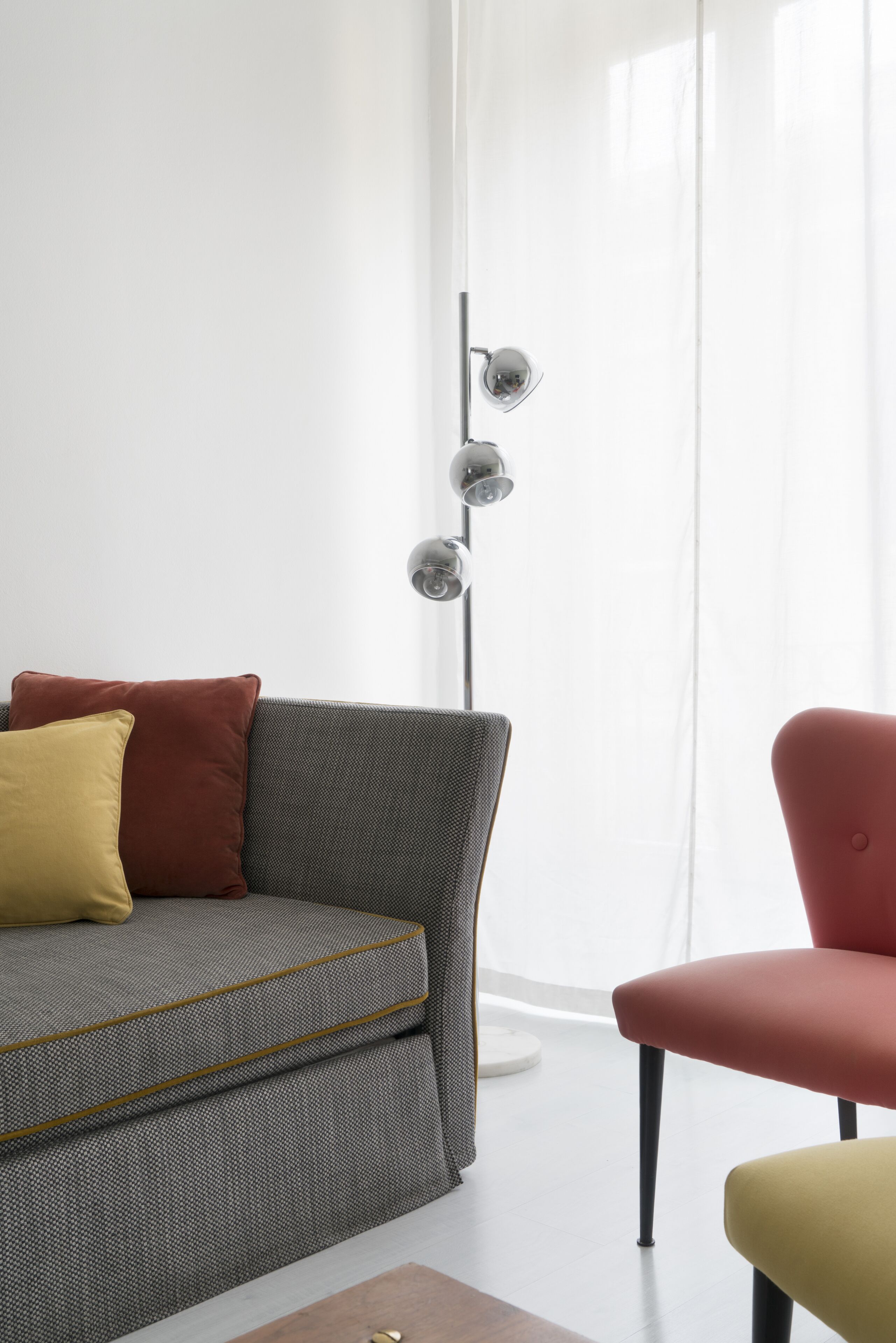 Ein modernes Wohnzimmer mit einem grauen Sofa, einem roten Sessel und einer Stehlampe.