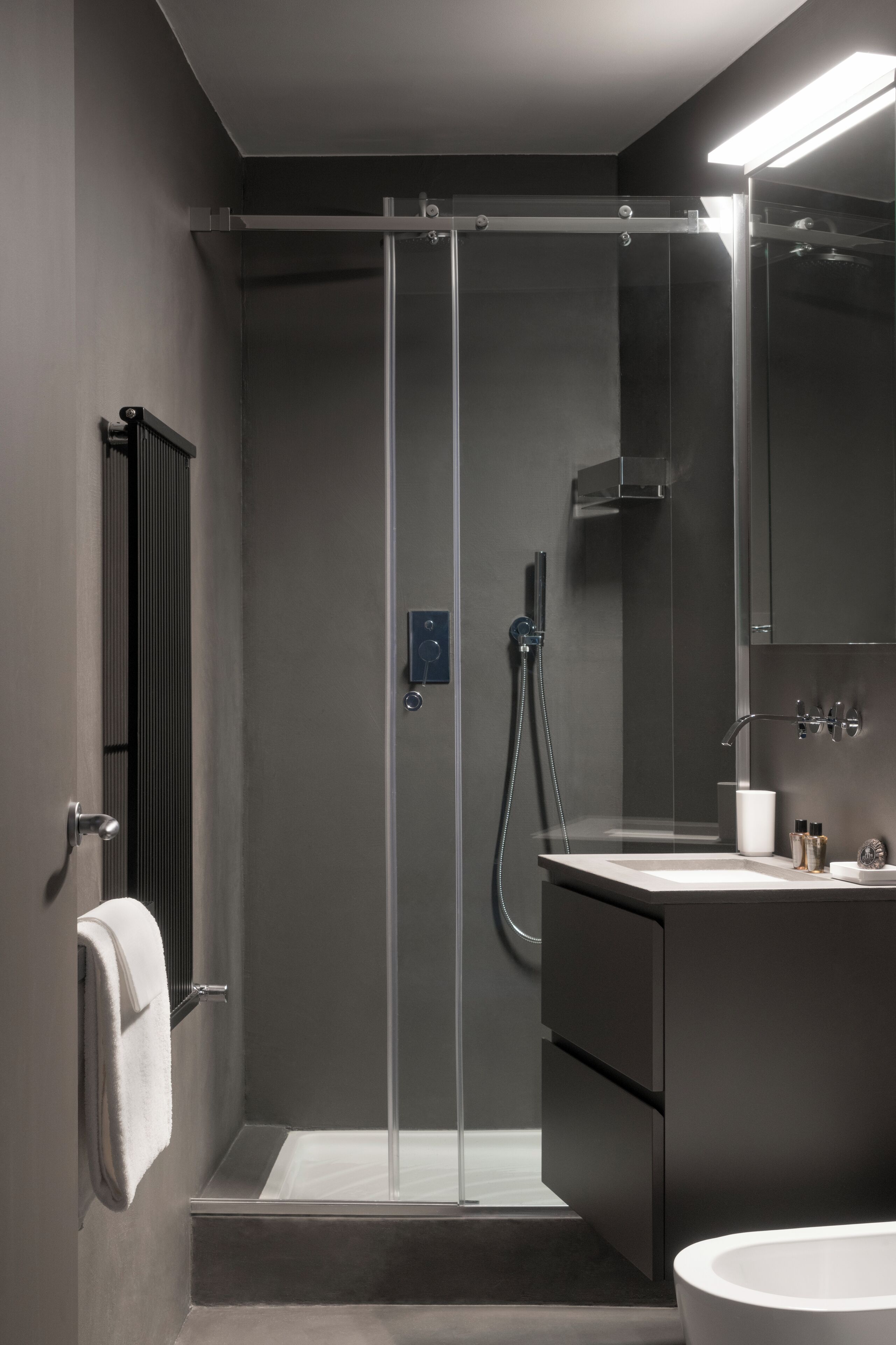 A modern bathroom with a glass-enclosed shower, a white bathtub, and a vanity with a mirror.