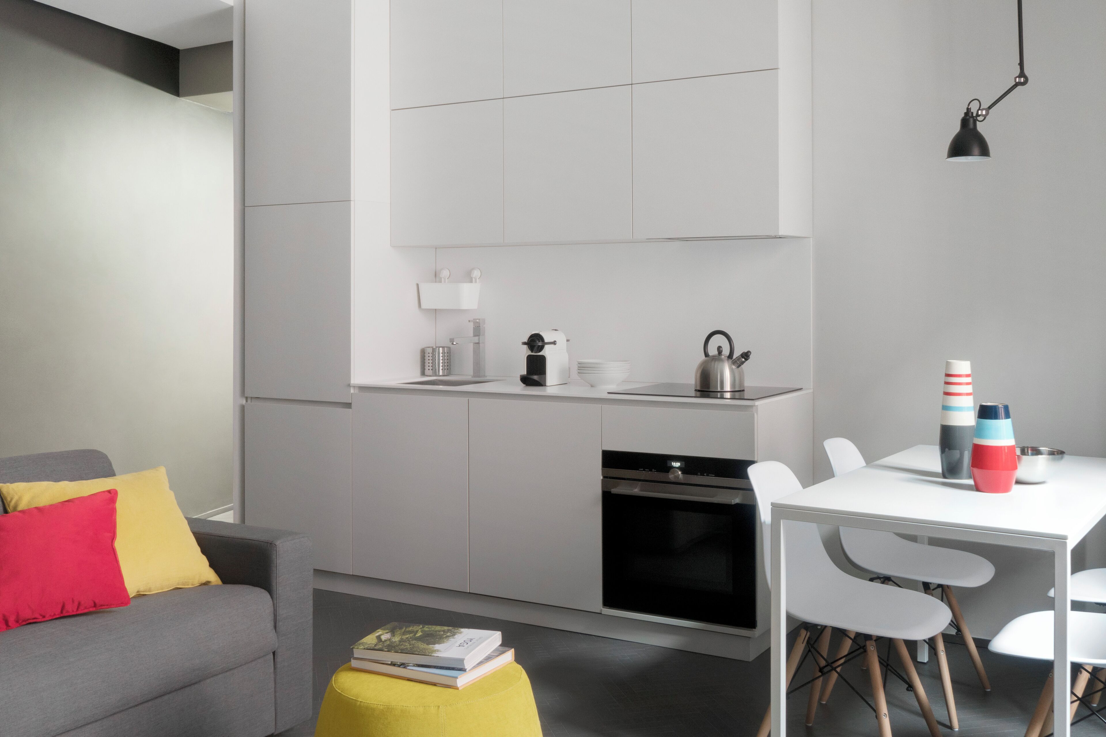 Una cucina moderna con mobili bianchi, un forno nero e un tavolo da pranzo bianco con sedie.