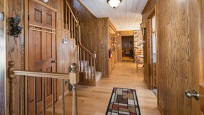 A wooden interior hallway with a staircase, wooden doors, and a patterned rug. - Tree Haven (Yosemite National)