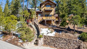 A lodge with a stone facade, wooden balconies, and a stone staircase leading to the entrance. - Tree Haven (Yosemite National)