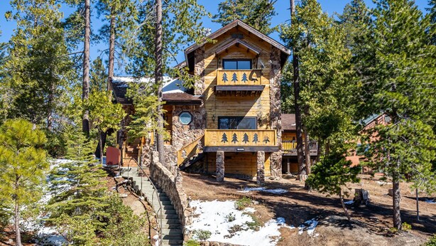 A log cabin with a stone staircase leading to the entrance, surrounded by pine trees. - Tree Haven (Yosemite National)