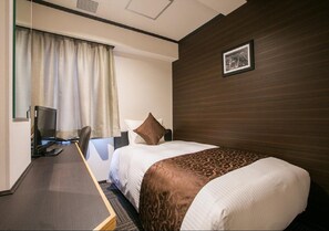 Relax in a stylish room with a large bed, desk, and window with curtains.