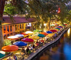 Un restaurante a la orilla del río con terraza y sombrillas de colores.