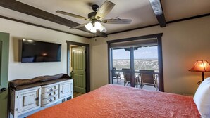Une chambre avec un lit, un ventilateur de plafond, une télévision, une commode et un balcon avec vue.