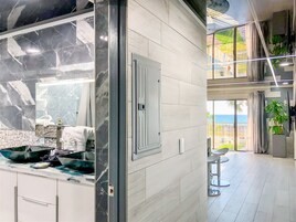 A modern kitchen with a large marble backsplash, a built-in oven, and a view of the ocean through large windows.