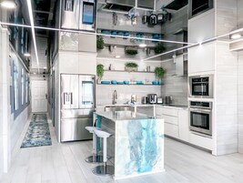 A modern kitchen with stainless steel appliances, a marble island, and a built-in oven.