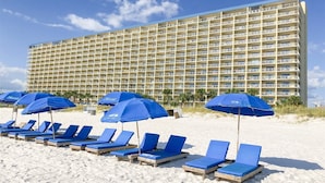 Ett hotell med flera balkonger och ett område vid stranden med solstolar och parasoller.