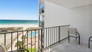 A balcony with a view of a beach and a pool.