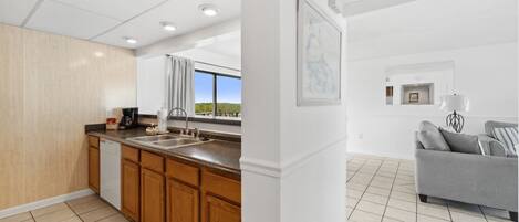 A modern kitchen with wooden cabinets, a built-in dishwasher, and a large window offering a view.