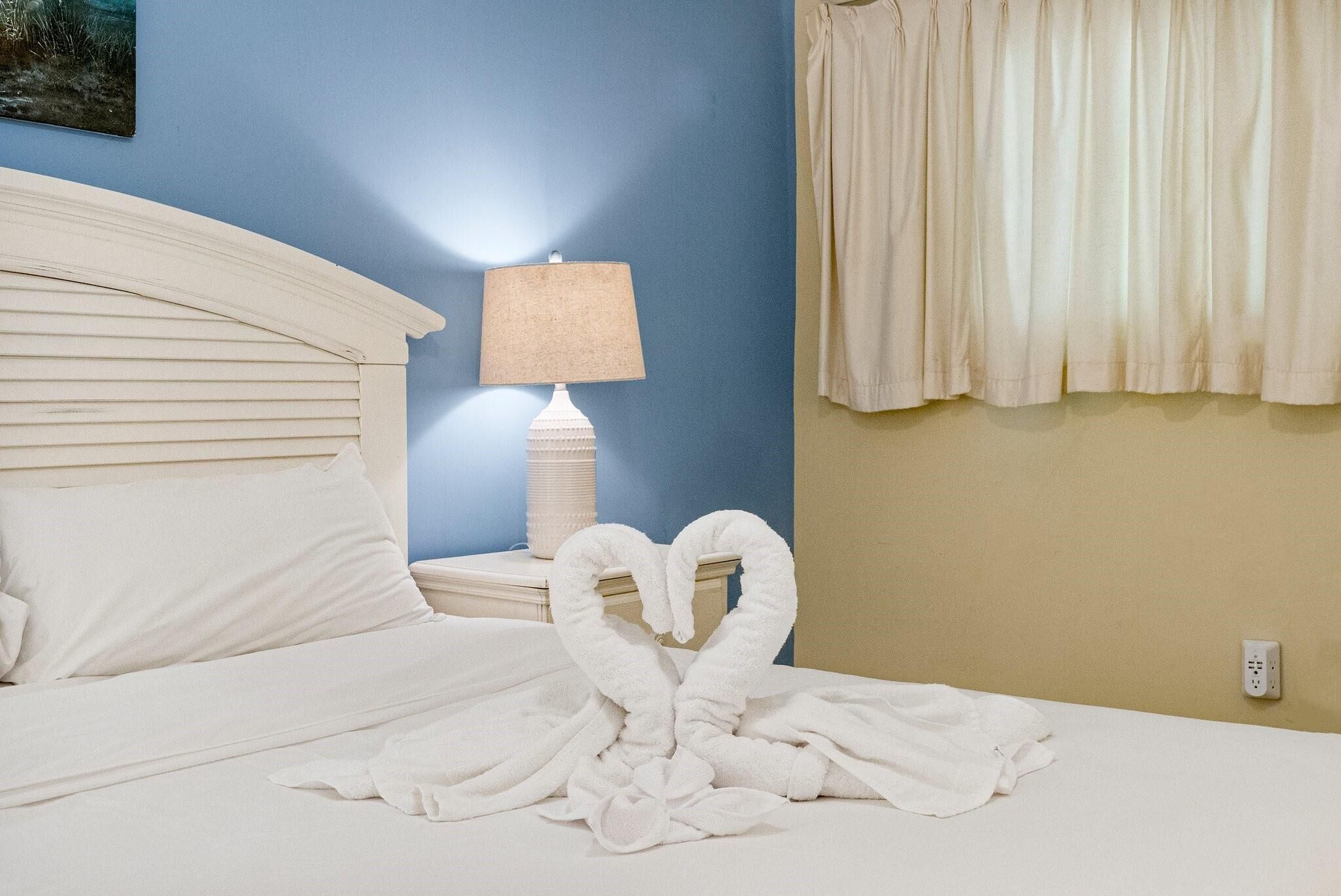Una habitación de hotel con cama, lámpara y ventana con cortinas.