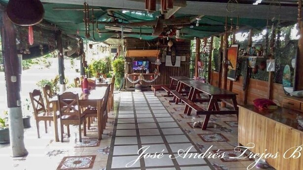 A restaurant with outdoor seating, a tiled floor, and a green awning. - Cabinas Manawada (Puerto Jiménez)