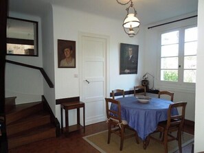 Un coin repas avec une table ronde, des chaises, une nappe bleue et un lustre.