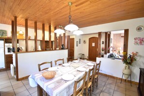 Enjoy meals in this dining area with a long table, chandelier, and kitchenette.