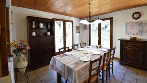 A dining area with a wooden ceiling, a table set for four, and a cabinet with dishes.
