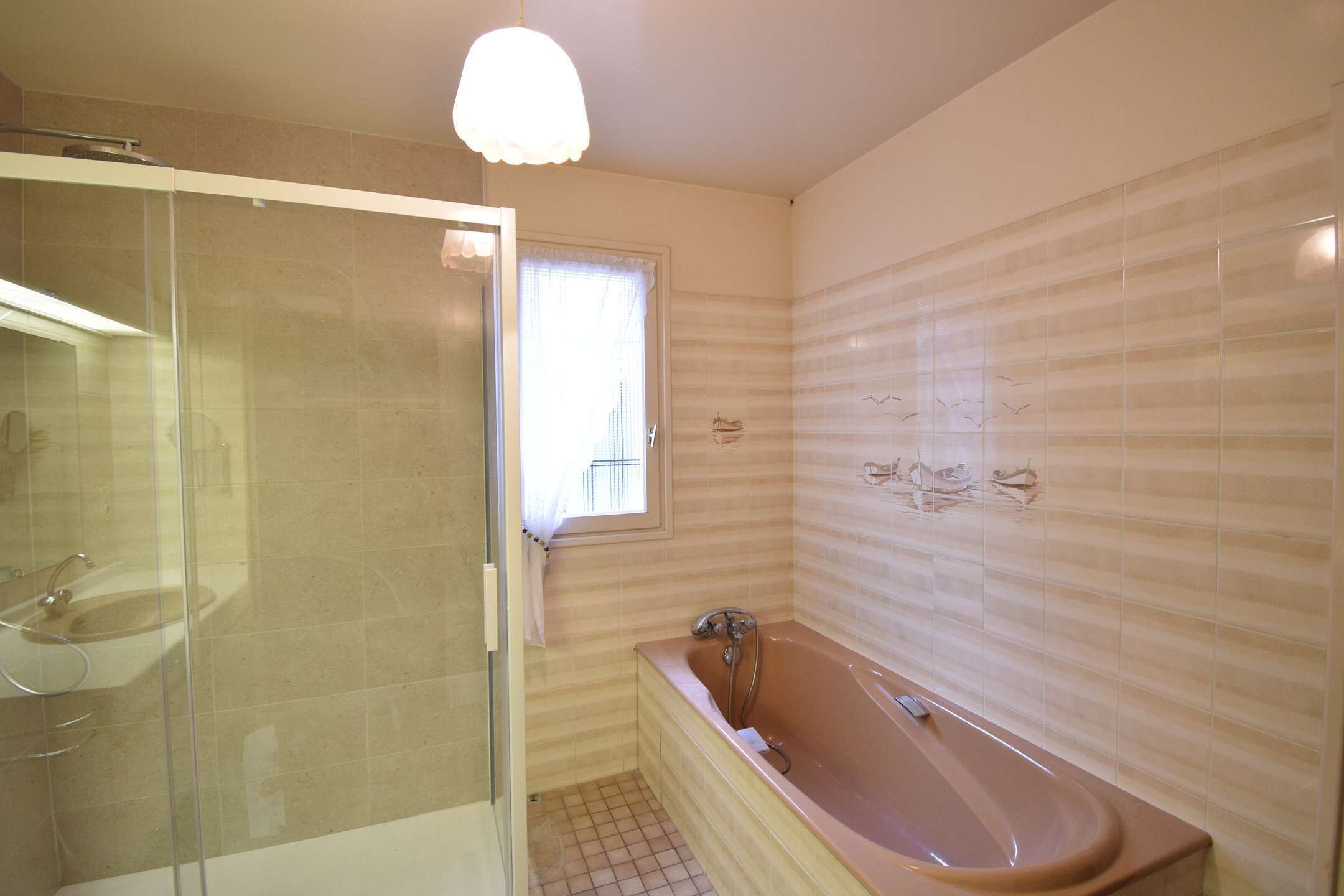 Une salle de bain avec une douche à parois de verre, une baignoire et une fenêtre.