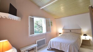 A bedroom with a bed, a nightstand, a lamp, a window, and a radiator.