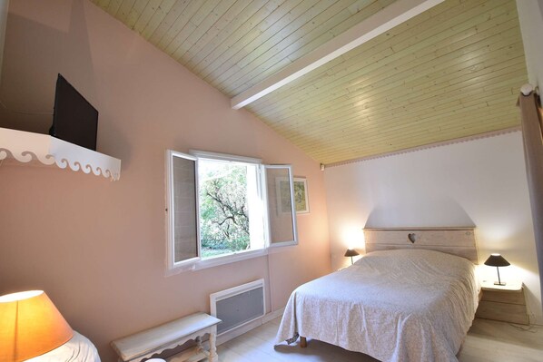 A bedroom with a bed, a nightstand, a lamp, a window, and a radiator. - Hossegor "OCEMY", Pleasant villa for 8 people. (Soorts-Hossegor)