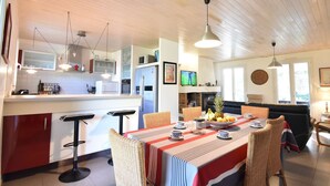 A modern kitchen with a central island, bar stools, and a dining area with a table set for four.