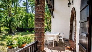 Une terrasse avec une table et des chaises, entourée d’un mur de briques et d’une rambarde en bois.
