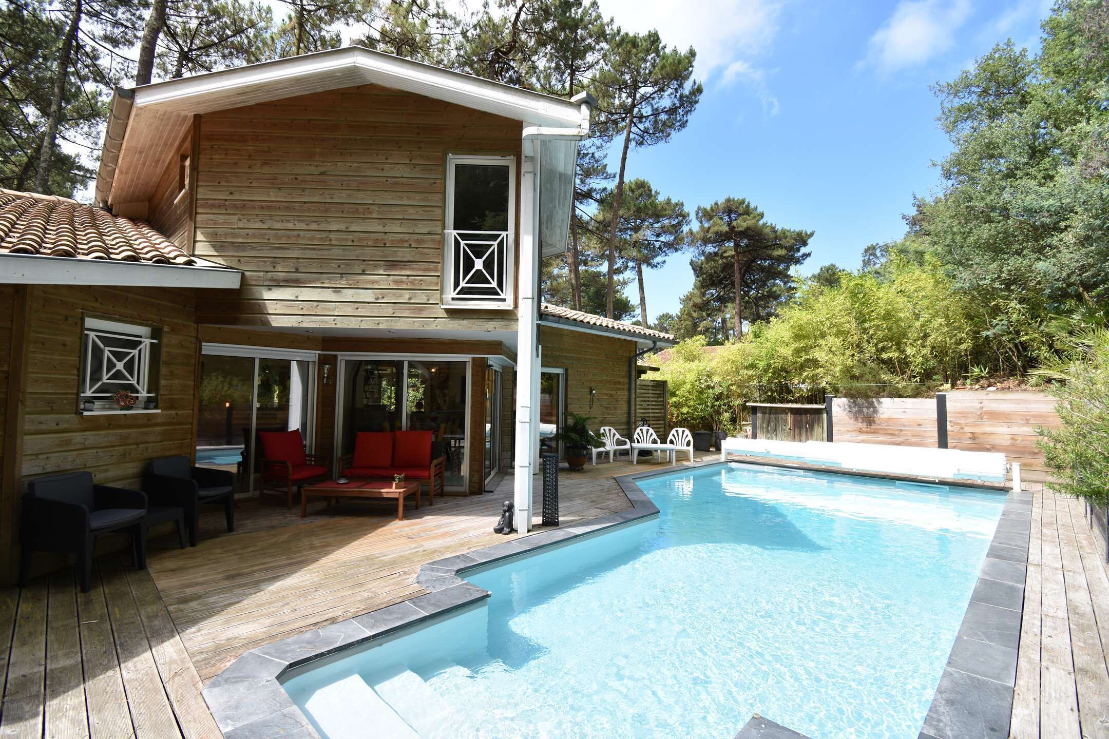 A wooden cabin with a swimming pool, outdoor seating, and a covered patio area.
