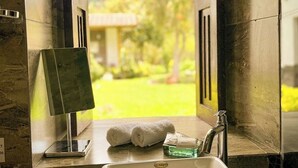 Une salle de bain avec une grande fenêtre, un lavabo et un miroir.