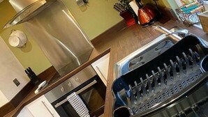 A kitchen with a stainless steel pot, a kettle, and a sink with a utensil holder.