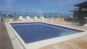 A swimming pool with lounge chairs and a view of the sea. - Flat Frente para o Mar Praia de Iracema (Fortaleza)
