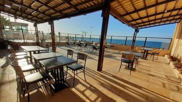 An outdoor patio area with tables and chairs, a covered seating area, and a view of the ocean. - Flat Frente para o Mar Praia de Iracema (Fortaleza)