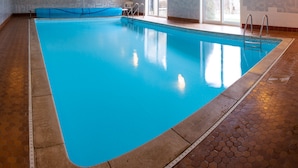 Une piscine intérieure à l’eau claire, avec un bord bleu et un sol carrelé.