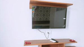 Een wandtelevisie met een houten tv-meubel eronder.