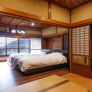 Un dormitorio japonés tradicional con cama de madera, puertas correderas y vistas al exterior.