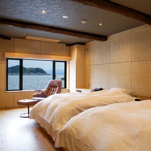 Un dormitorio con dos camas, una silla, un ventanal con vista al mar y techo de madera.