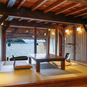 Un intérieur en bois avec une table et des chaises, une vue sur la mer et un plafond en bois.