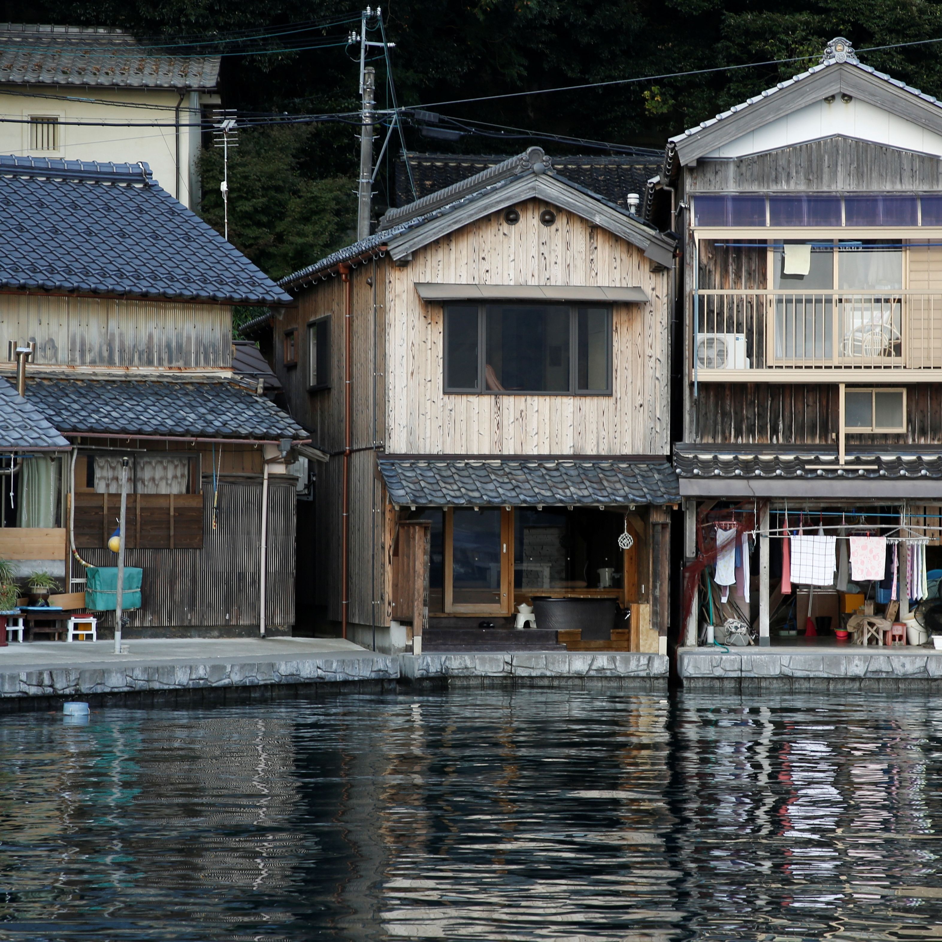 A traditional wooden house with a tiled roof, a wooden porch, and a small outdoor seating area.