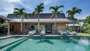 Un resort moderno con piscina, tumbonas y palmeras.