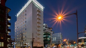A SuperHotel building with multiple floors and balconies, surrounded by other buildings and a busy street at night. - Super Hotel Premier Saitama Omiyaeki Higashiguchi (Saitama)