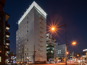 Een meerhoog hotel met een opvallend bord bovenop, meerdere ramen en een modern architectuur.