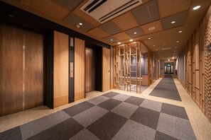 Een hotelgang met houten deuren, een geruit tapijt en een houten wand met een structuur.