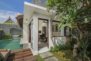 A modern villa with a private pool, a dining area, and a view of the surrounding landscape.