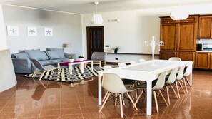 Una sala de estar moderna con un sofá gris, una mesa de comedor con sillas y una cocina con armarios de madera.